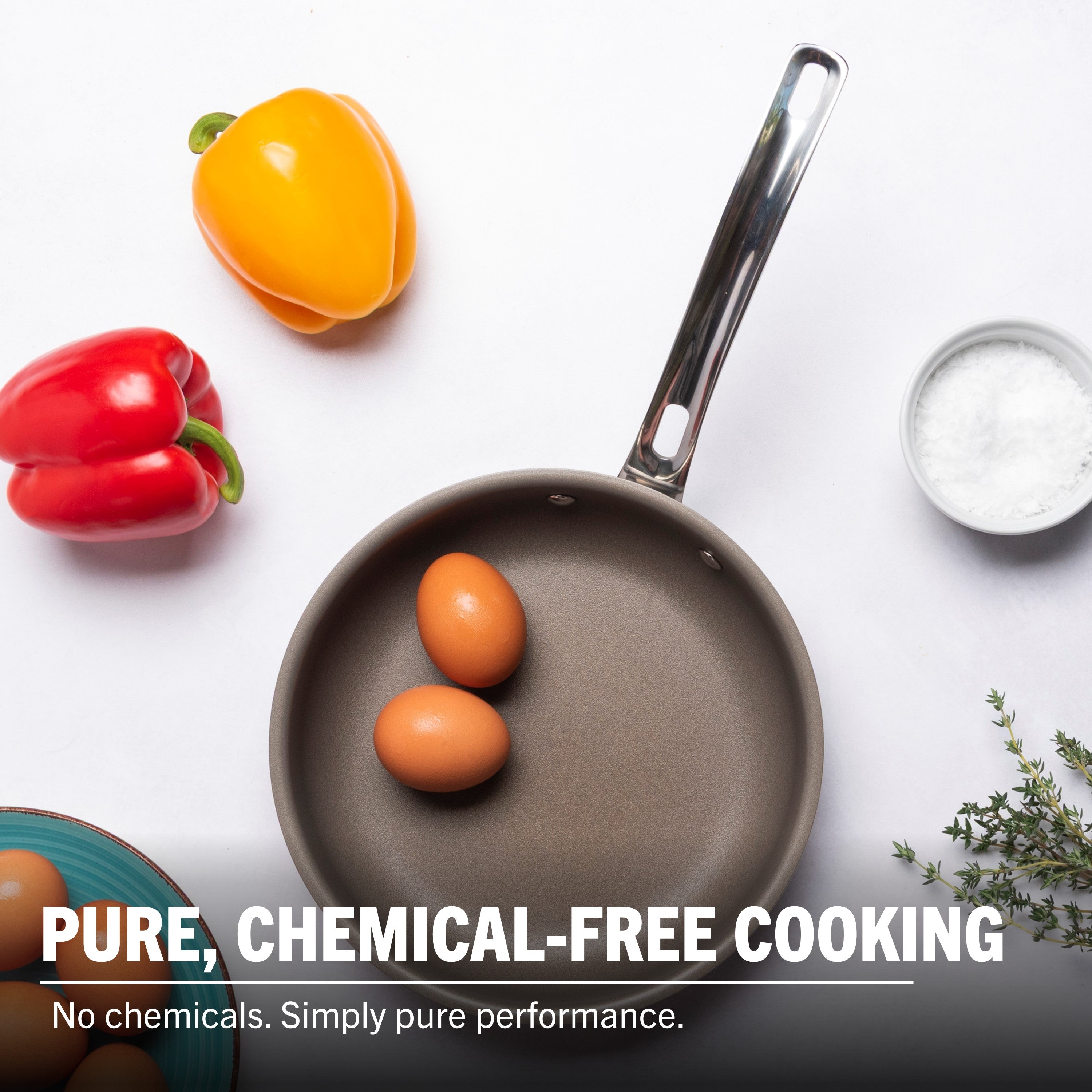 A Viking Culinary Products PureGlide Pro 3-Ply 8 Inch Fry Pan with two eggs sits on a white surface, surrounded by yellow and red bell peppers, a bowl of salt, blue plate, and thyme. Text reads: Pure cooking. No chemicals—just healthy performance.