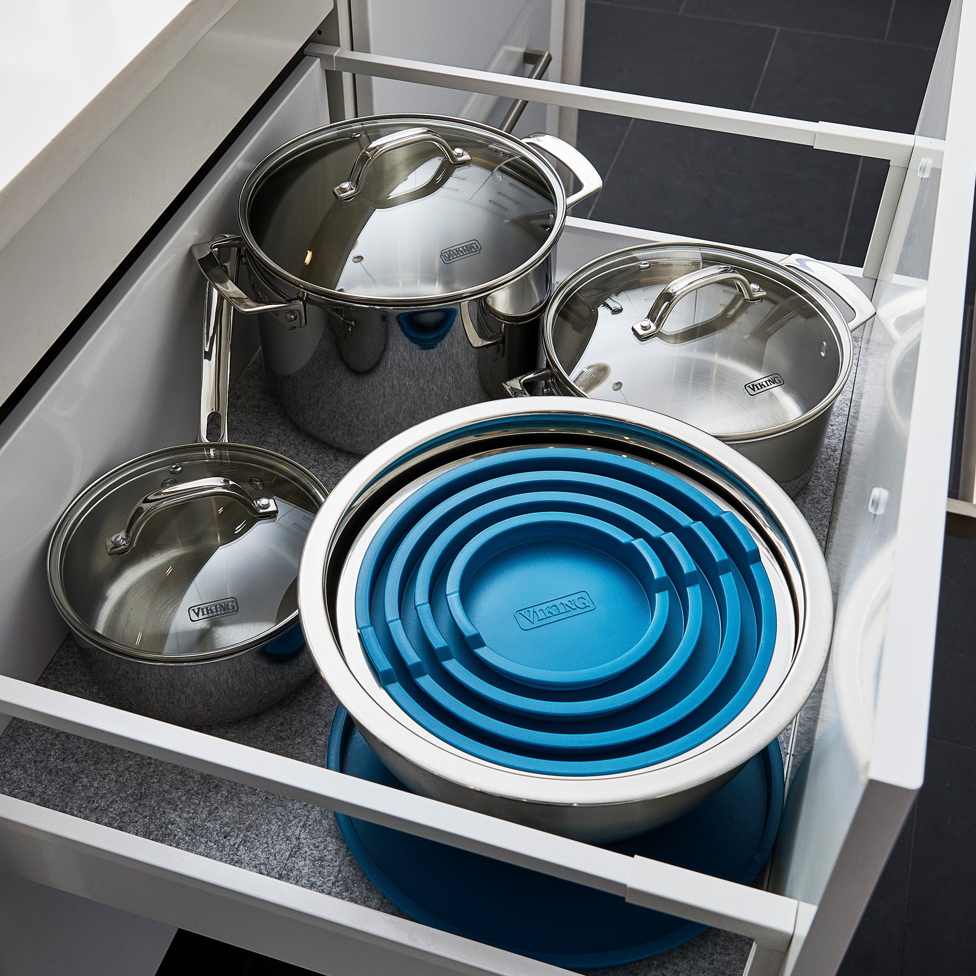 Open kitchen drawer with three Viking Culinary Products stainless steel pots and the Viking 10-Piece Stainless Steel Mixing Bowl Set with teal lids, all neatly organized.