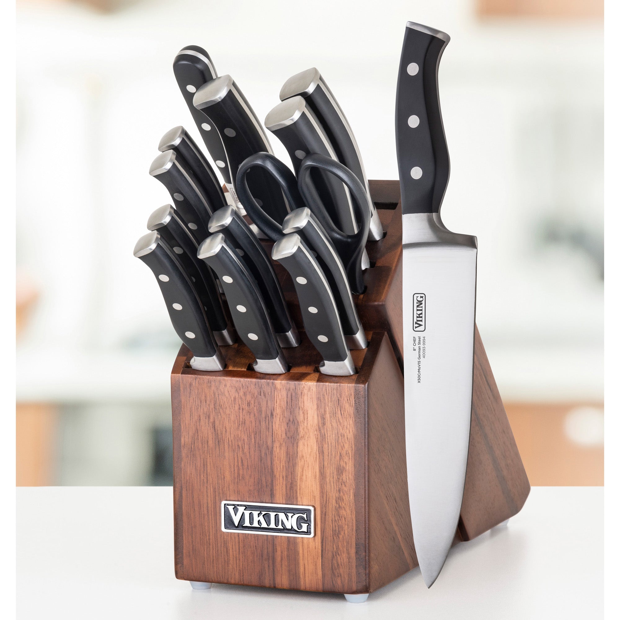 The Viking 15-Piece Stainless Steel Cutlery Set by Viking Culinary Products features black-handled knives and kitchen shears in an acacia wood block, with a chefs knife shown in front on a white surface.