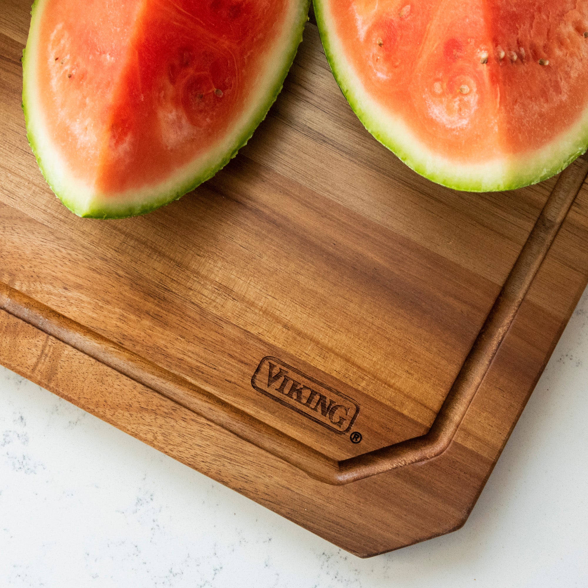 Two watermelon slices rest on a Viking Culinary Products Acacia Carving Board with Juice Groove, placed on a light countertop.