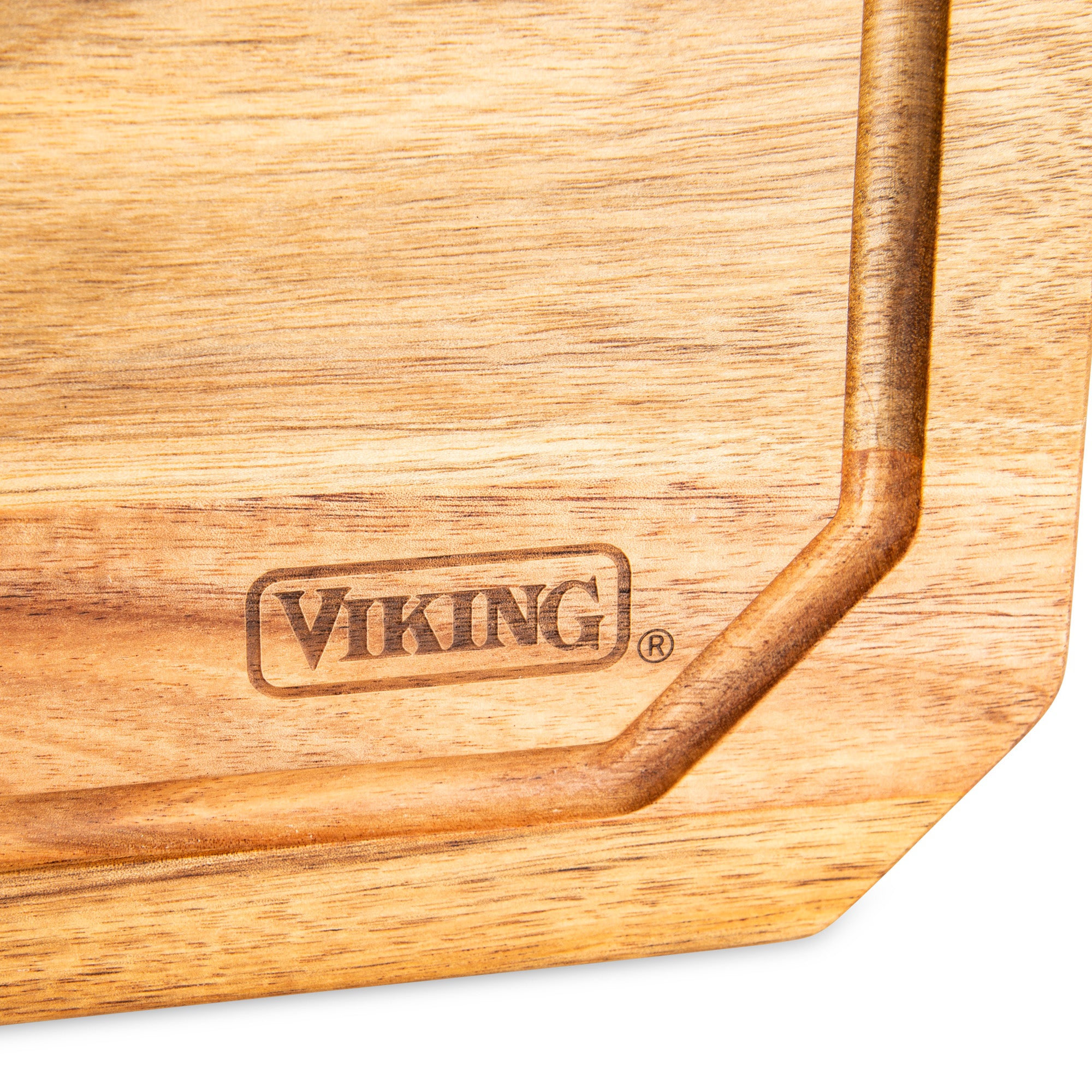 A close-up of the Viking Acacia Carving Board with Juice Groove by Viking Culinary Products, showcasing the engraved VIKING® logo near its deep juice groove on acacia wood.