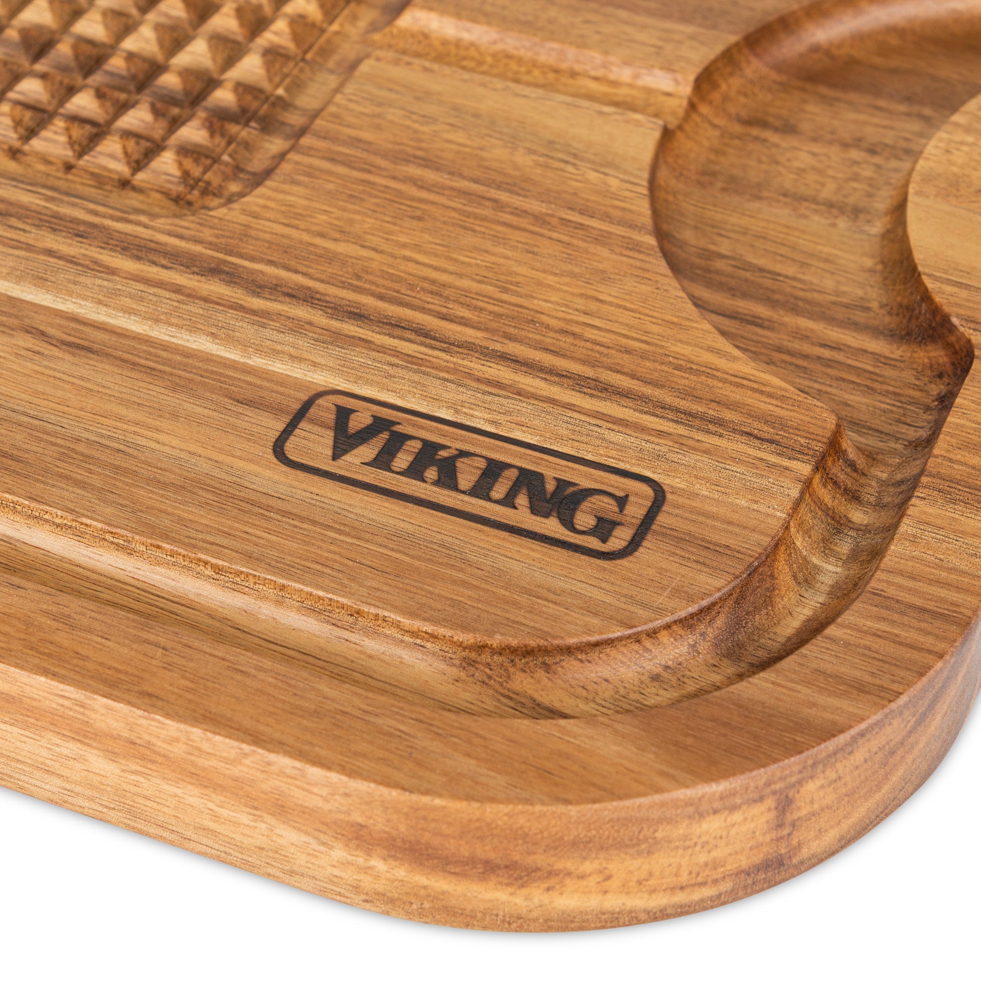 A close-up of the Viking Acacia Wood Cutting Board by Viking Culinary Products, featuring a grooved section, VIKING engraved on the surface, and paired with a 3-piece stainless steel carving set.
