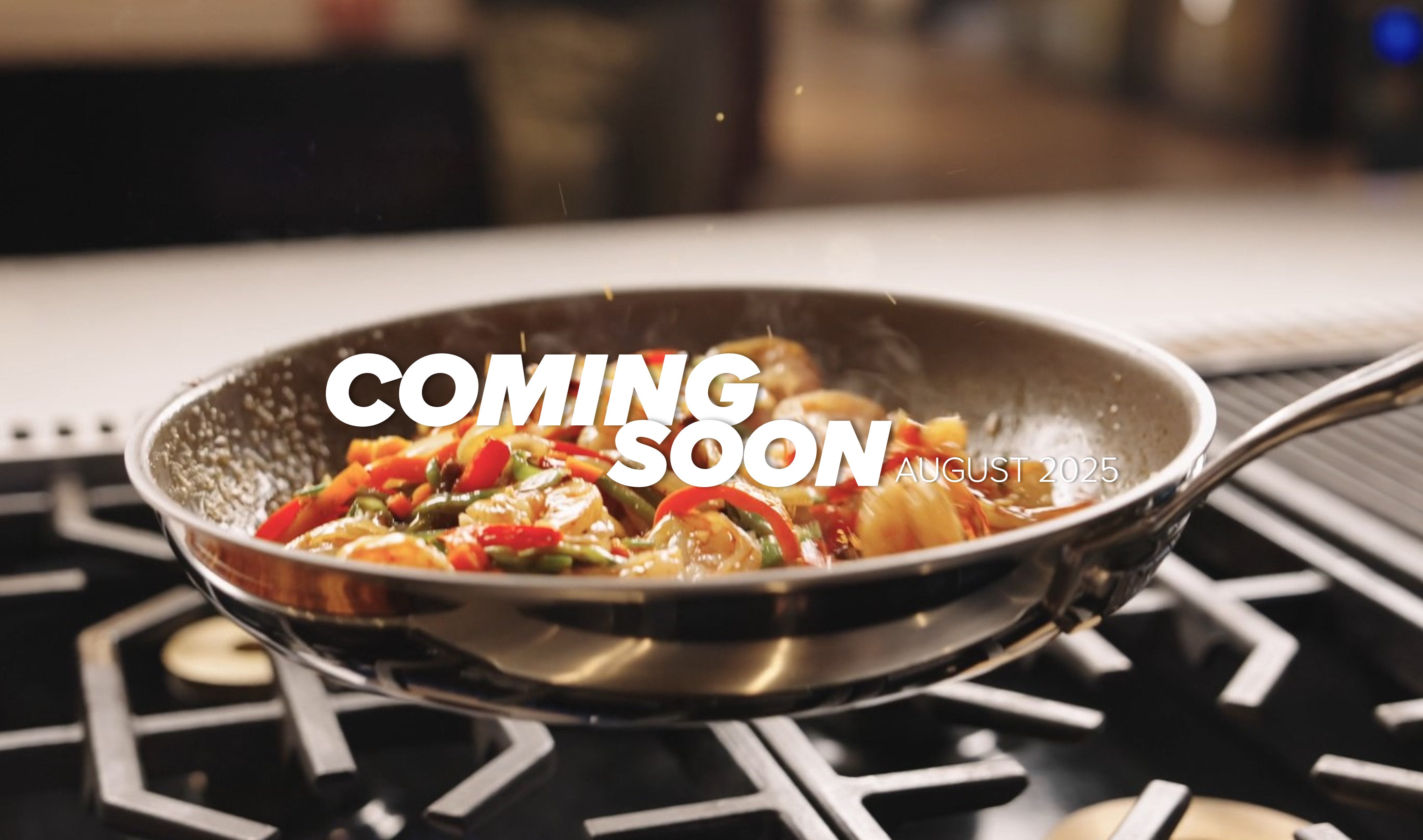 Close-up of a stainless steel pan on a stove, cooking a colorful dish with vegetables and pieces of meat. The word Viking is engraved on the pans handle. Steam rises from the hot food.