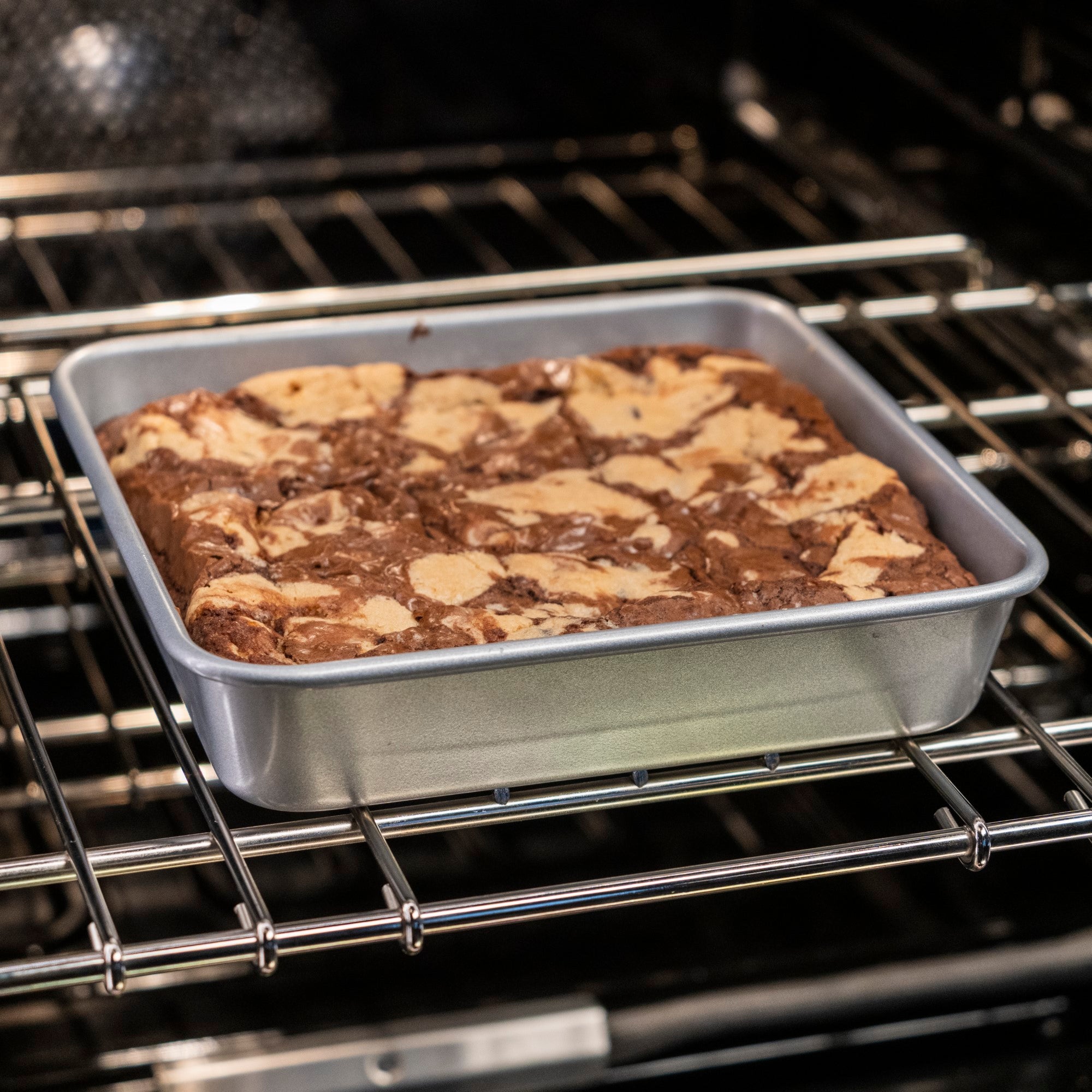 A Viking Culinary Products Aluminized Steel Nonstick 9-inch Square Cake Pan bakes marbled brownies with a beautifully swirled chocolate and cream cheese top inside the oven.