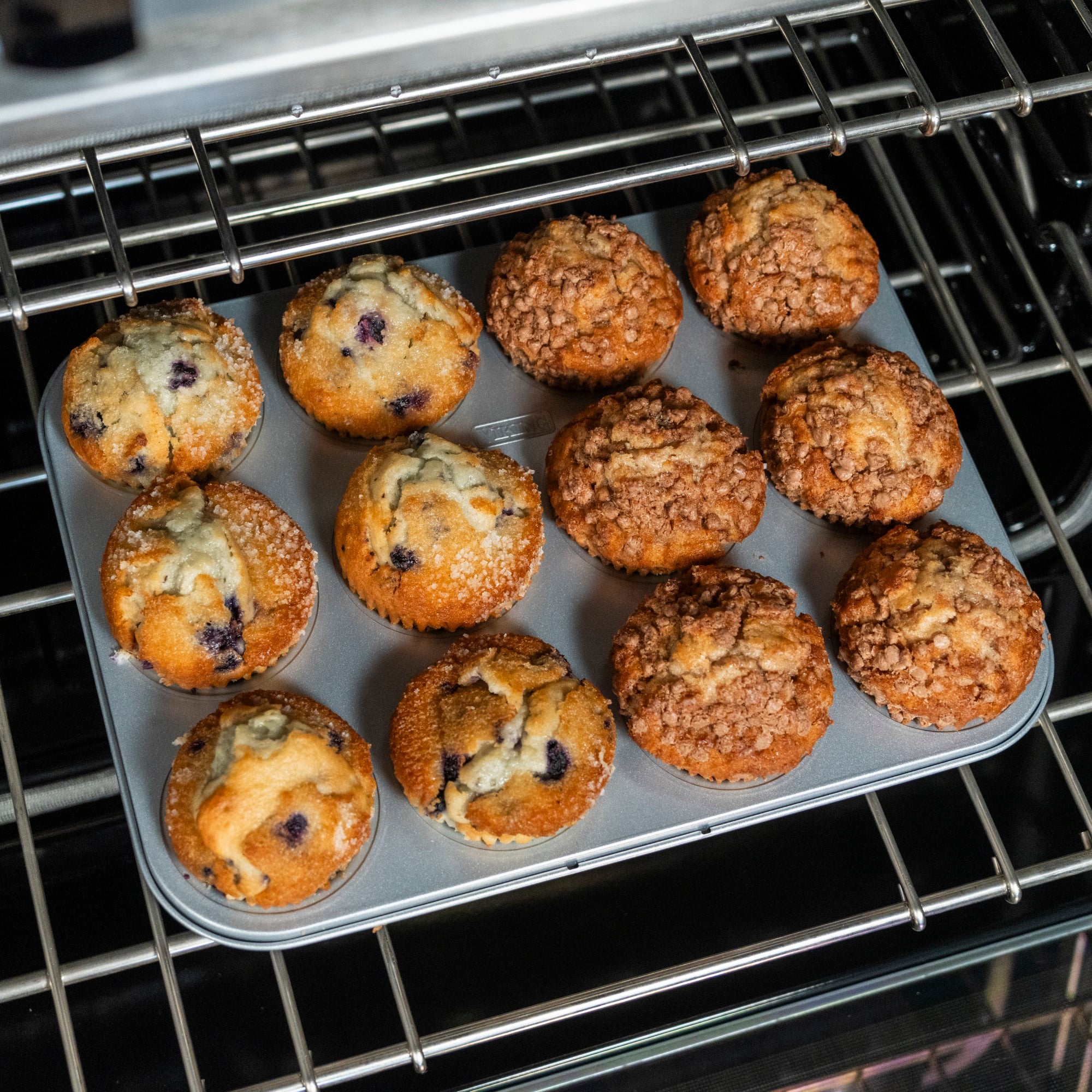 The Viking Aluminized Steel Nonstick 12-Cup Muffin Pan by Viking Culinary Products bakes six blueberry muffins and six crumb-topped treats to golden brown perfection, while the nonstick surface ensures easy release from the pan.